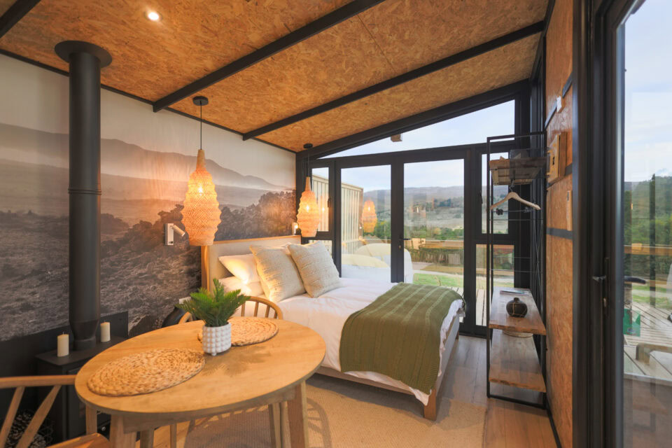 Aardvark: bed and dining table below a mountain mural and the wood-burner flue, Old Mac Daddy, Elgin Valley