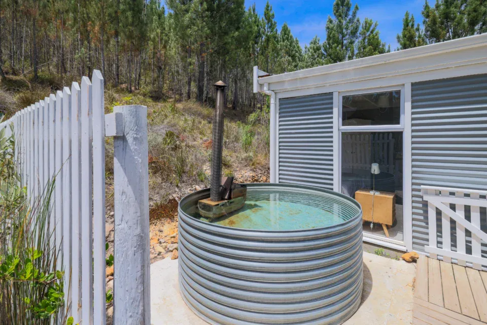 Daddy's Villa: galvanised wood-fired hot tub beside the villa, pines behind, Old Mac Daddy, Elgin Valley