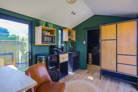 Intak: green-walled kitchenette with a leather armchair and timber wardrobe, Old Mac Daddy, Elgin Valley