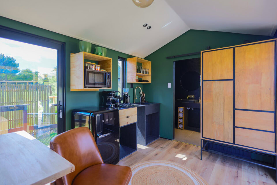 Intak: green-walled kitchenette with a leather armchair and timber wardrobe, Old Mac Daddy, Elgin Valley