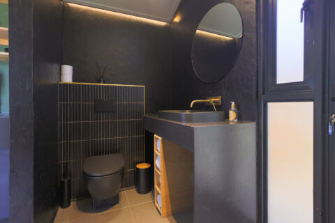 Intak: black bathroom with a round mirror and brass tap, Old Mac Daddy, Elgin Valley