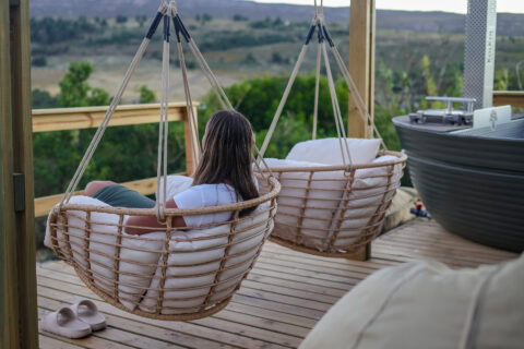 Intak: guest in a hanging rattan chair on the deck, looking over the valley, Old Mac Daddy, Elgin Valley