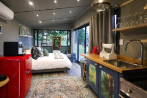 Kaapse Nooi: bed, red SMEG fridge and kitchenette with glass doors at the far end, Old Mac Daddy, Elgin Valley