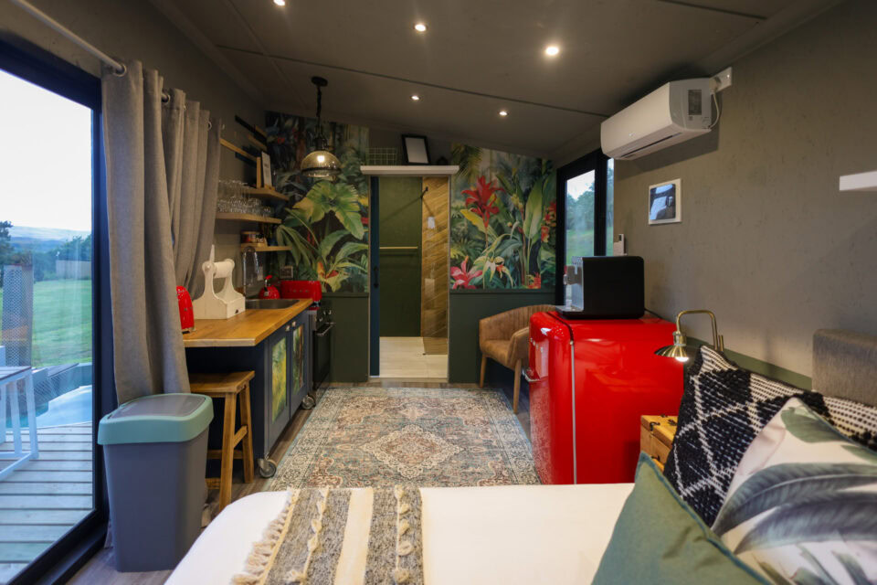 Kaapse Nooi: bed, kitchenette and red SMEG fridge below a tropical mural, Old Mac Daddy, Elgin Valley