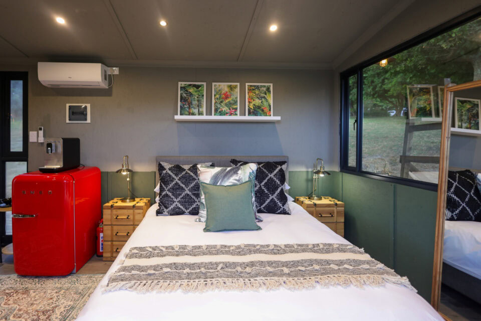 Kaapse Nooi: double bed with patterned cushions and a red SMEG fridge beside it, Old Mac Daddy, Elgin Valley