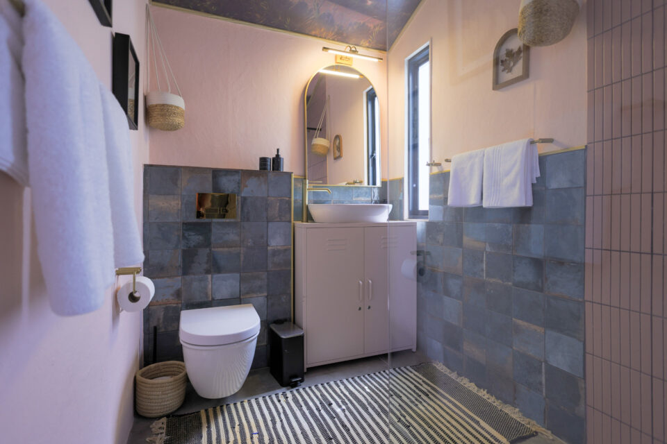 Palimpses: bathroom with pink walls, blue-grey tiles and an arched mirror, Old Mac Daddy, Elgin Valley