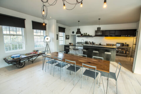 The School House: open-plan kitchen and long timber dining table under hanging bulbs, Old Mac Daddy, Elgin Valley