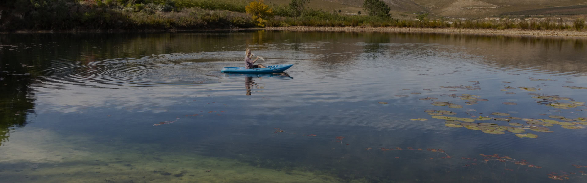 Kayaker on a still lake among lily pads, Old Mac Daddy, Elgin Valley
