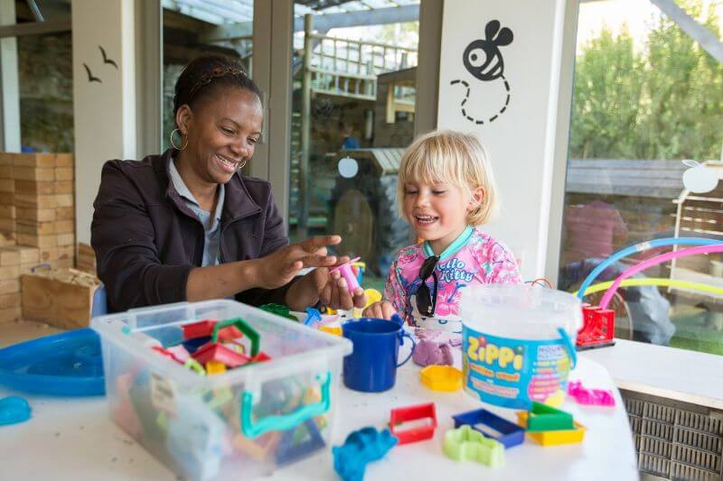 A carer and a little girl playing with toy blocks in the kids' playroom, Old Mac Daddy, Elgin Valley