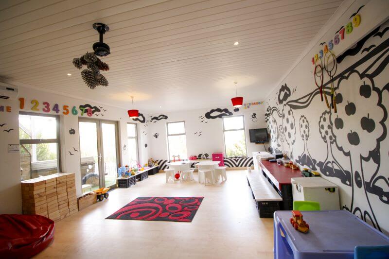 Kids' playroom with a bold black-and-white tree mural, small tables and a red rug, Old Mac Daddy, Elgin Valley