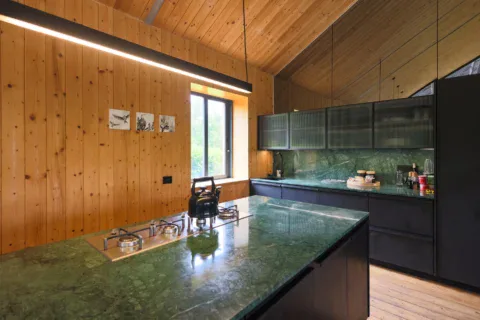 Apple Grove: kitchen with a green-stone island, gas hob and black cabinets against pine walls, Old Mac Daddy, Elgin Valley