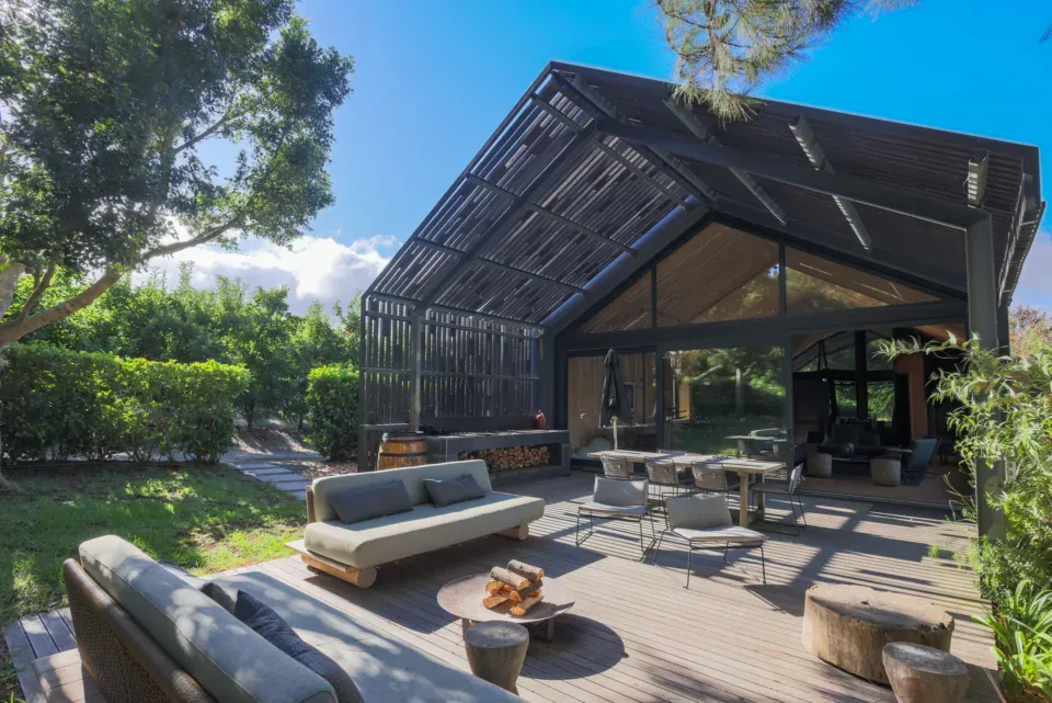 Apple Grove: the timber lodge behind its laser-cut steel screen, with a deck, fire bowl and lounge seating in the garden, Old Mac Daddy, Elgin Valley