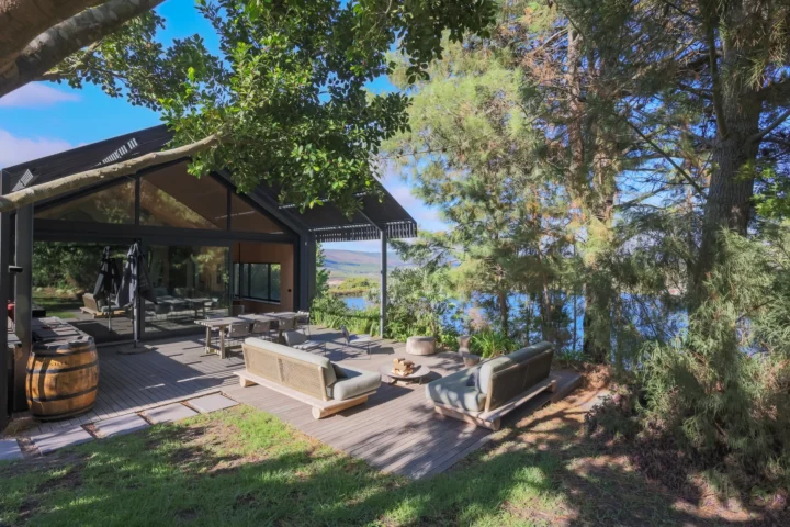 Apple Grove: the lodge from the lawn, with outdoor sofas and a wine barrel on the deck among the trees, Old Mac Daddy, Elgin Valley