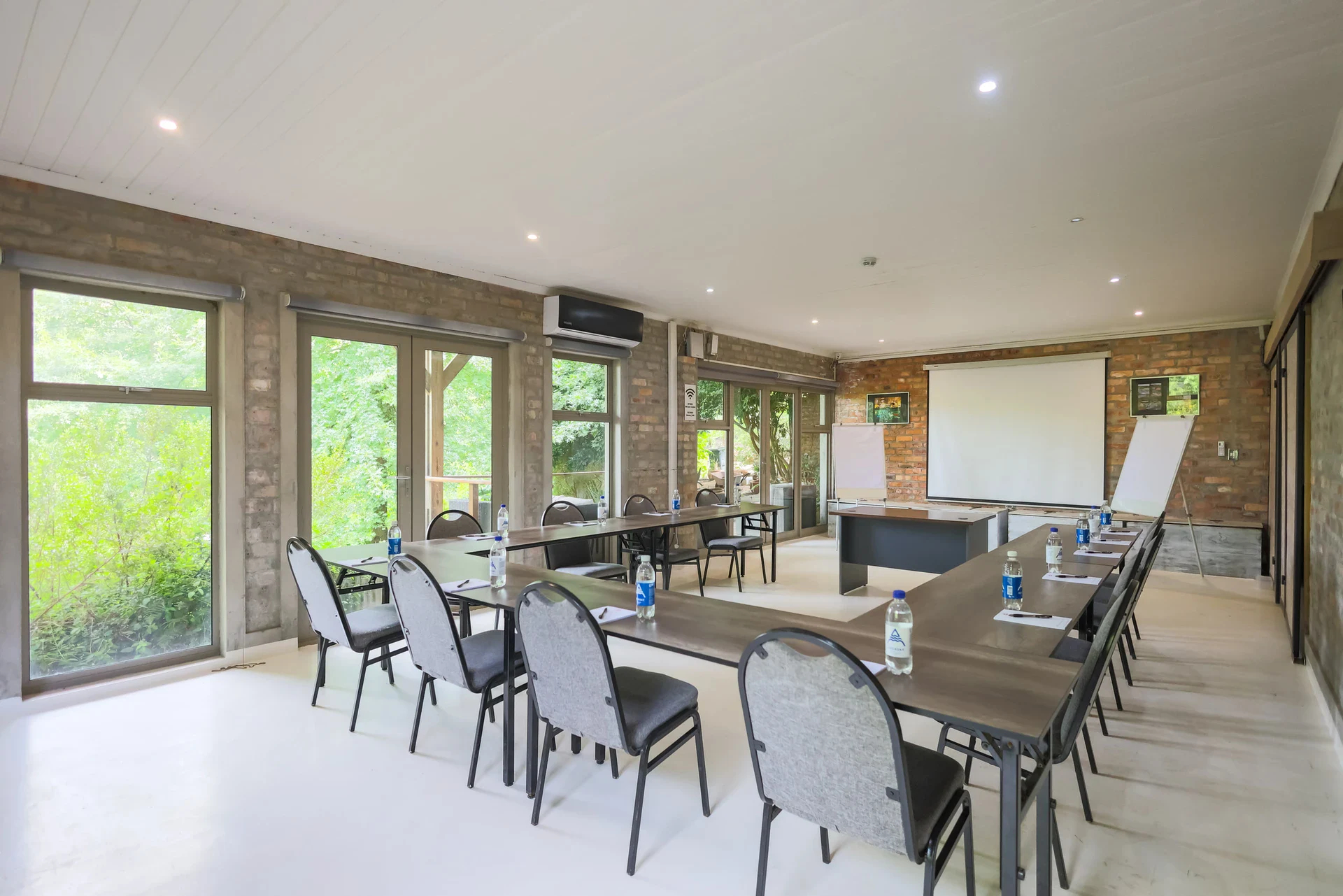 The conference room laid out in a U-shape with upholstered chairs, a projector screen and flip chart, garden through the windows, Old Mac Daddy, Elgin Valley
