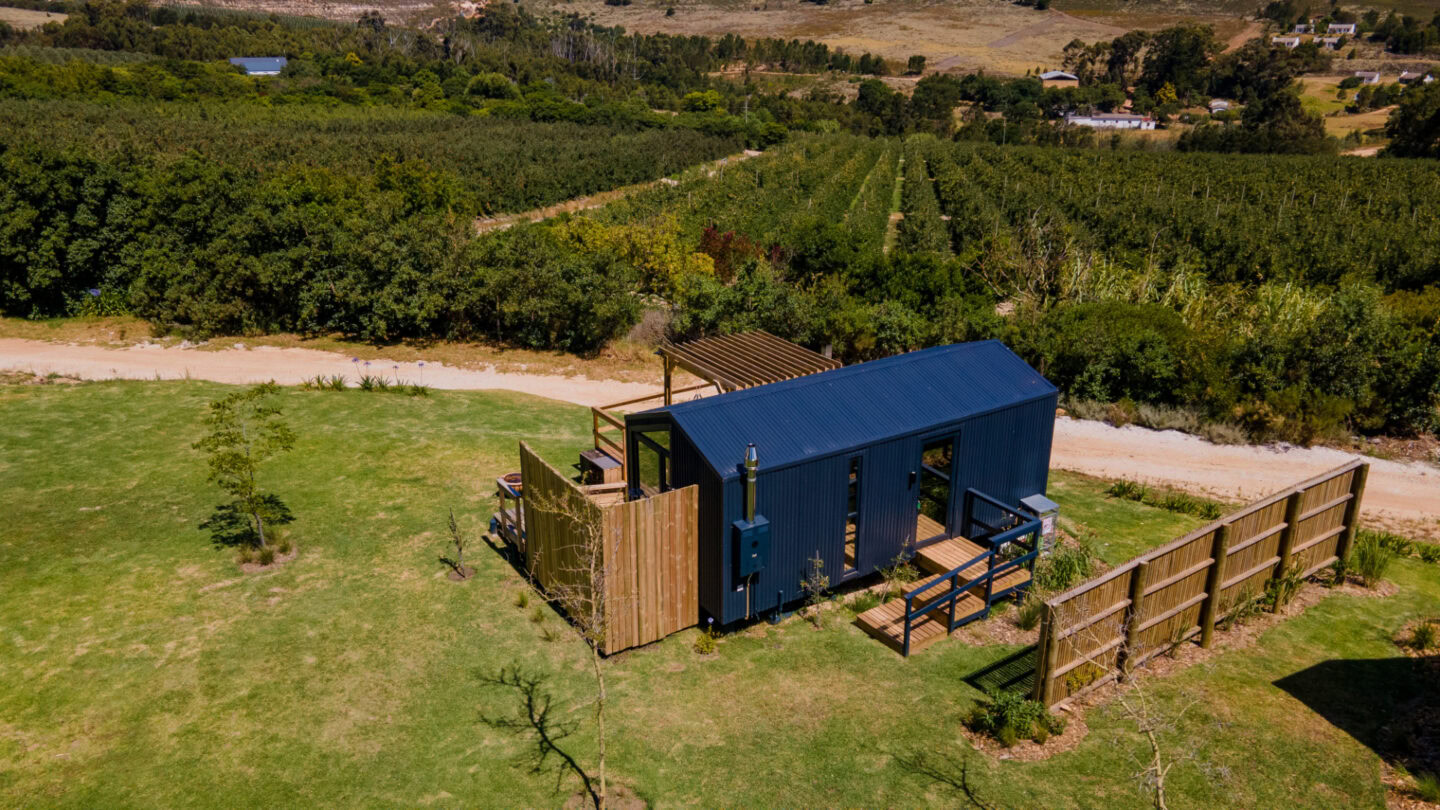 Klein Paradys: aerial view of a dark timber unit with a fenced deck beside the orchards, Old Mac Daddy, Elgin Valley