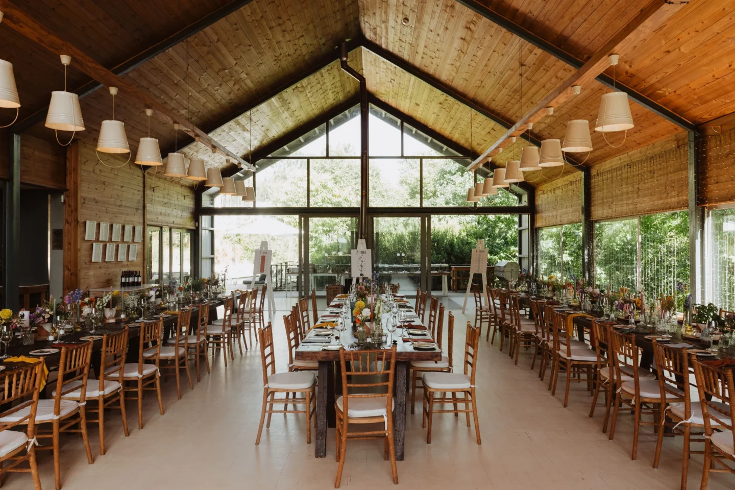 The Barn set for a wedding reception, long tables under the pitched timber roof and glass gable, Old Mac Daddy, Elgin Valley