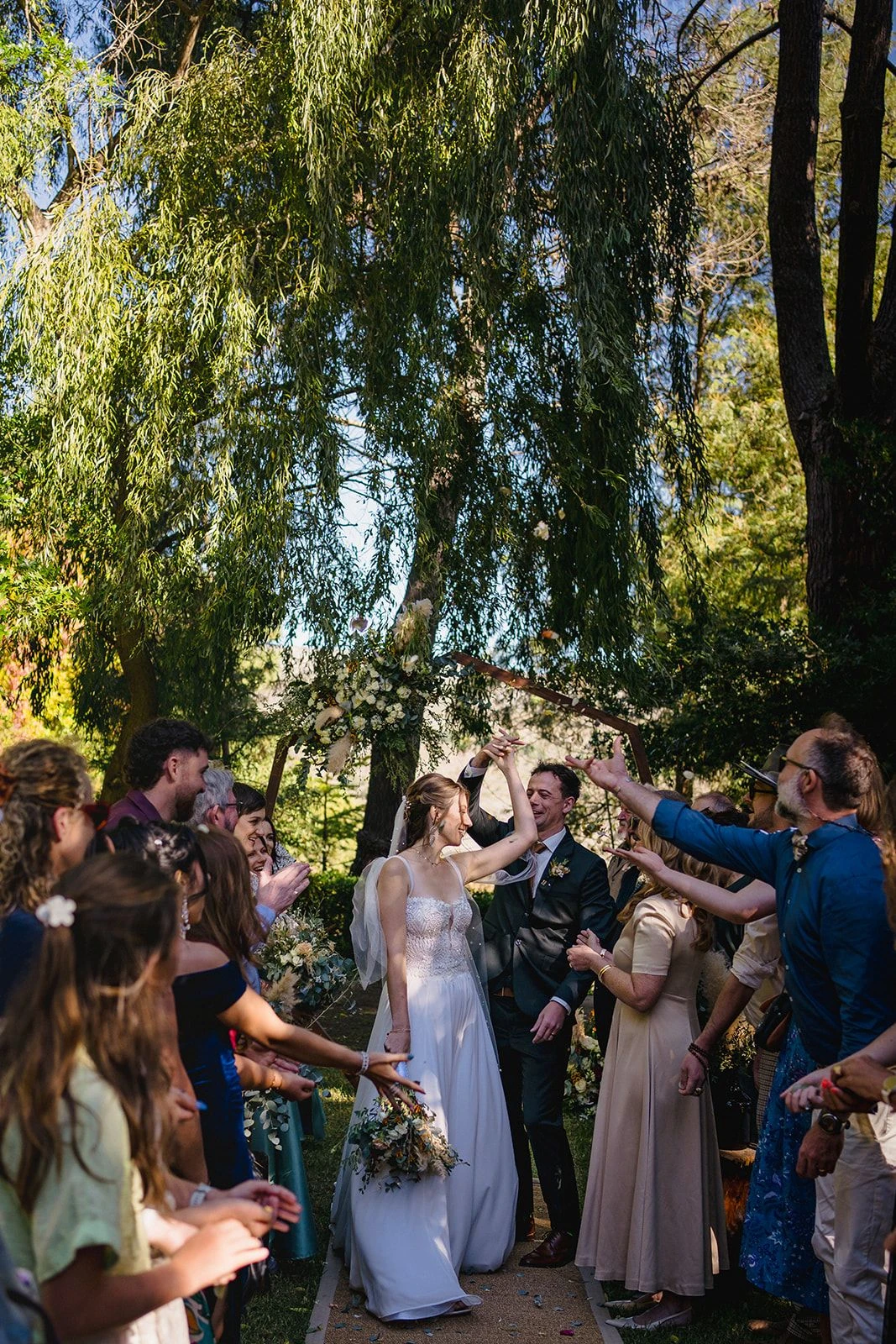 Bride and groom walking back down the aisle between cheering guests under the willows, Old Mac Daddy, Elgin Valley