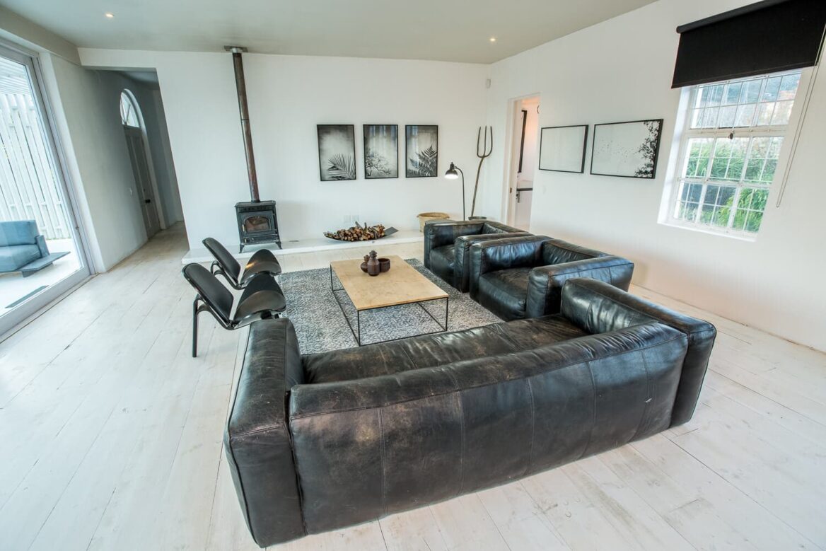 The School House: lounge with black leather sofas, a wood-burner and framed prints, Old Mac Daddy, Elgin Valley