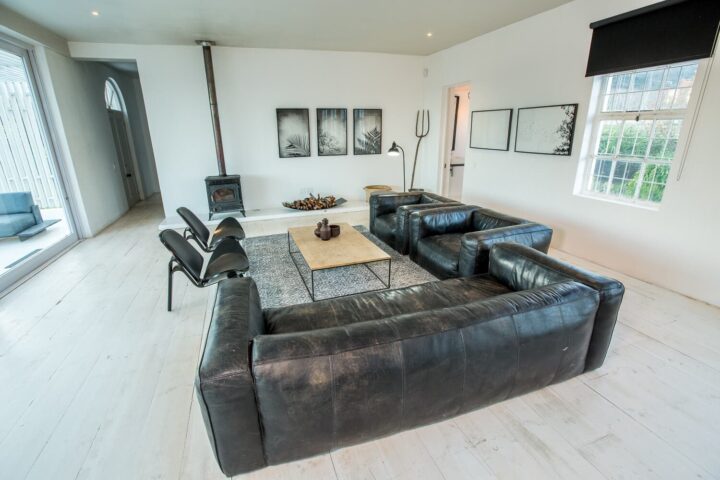 The School House: lounge with black leather sofas, a wood-burner and framed prints, Old Mac Daddy, Elgin Valley