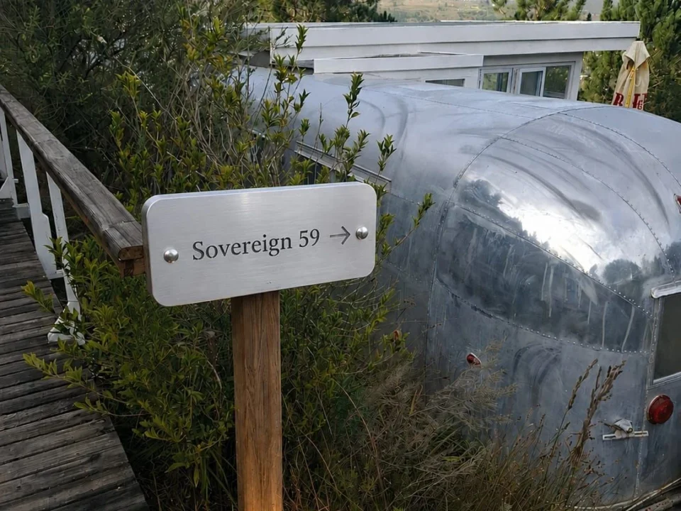Sovereign 59: the silver Airstream among fynbos, with its name sign beside the boardwalk, Old Mac Daddy, Elgin Valley