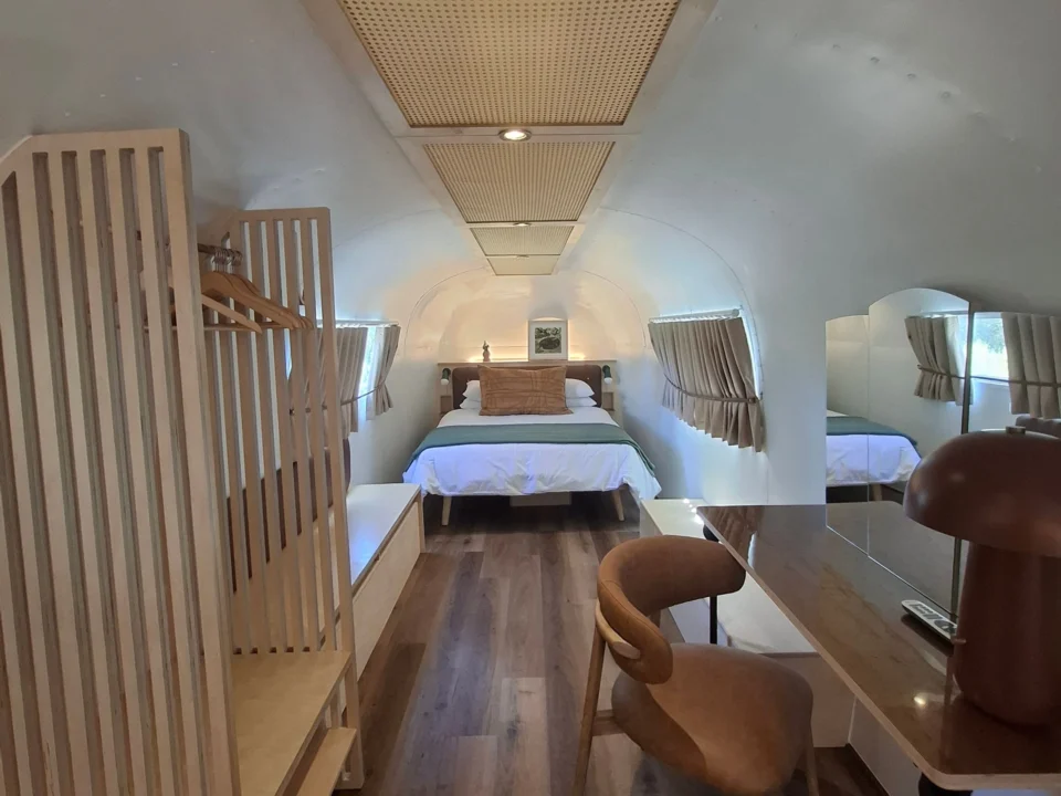 Sovereign 59: looking down the Airstream to the bed, past a desk, a leather chair and a cane ceiling panel, Old Mac Daddy, Elgin Valley