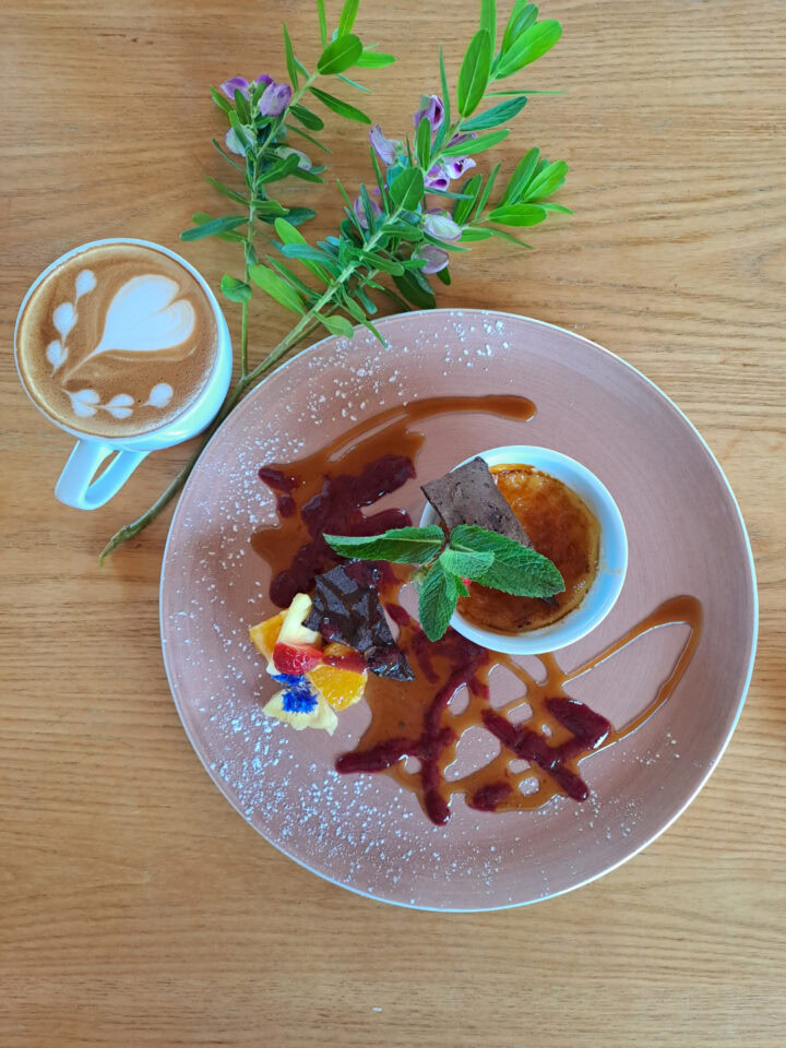 A plated dessert with caramel sauce and chocolate, beside a latte, Old Mac Daddy, Elgin Valley