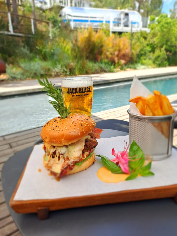 A burger, fries and a beer on a board beside the pool, Old Mac Daddy, Elgin Valley