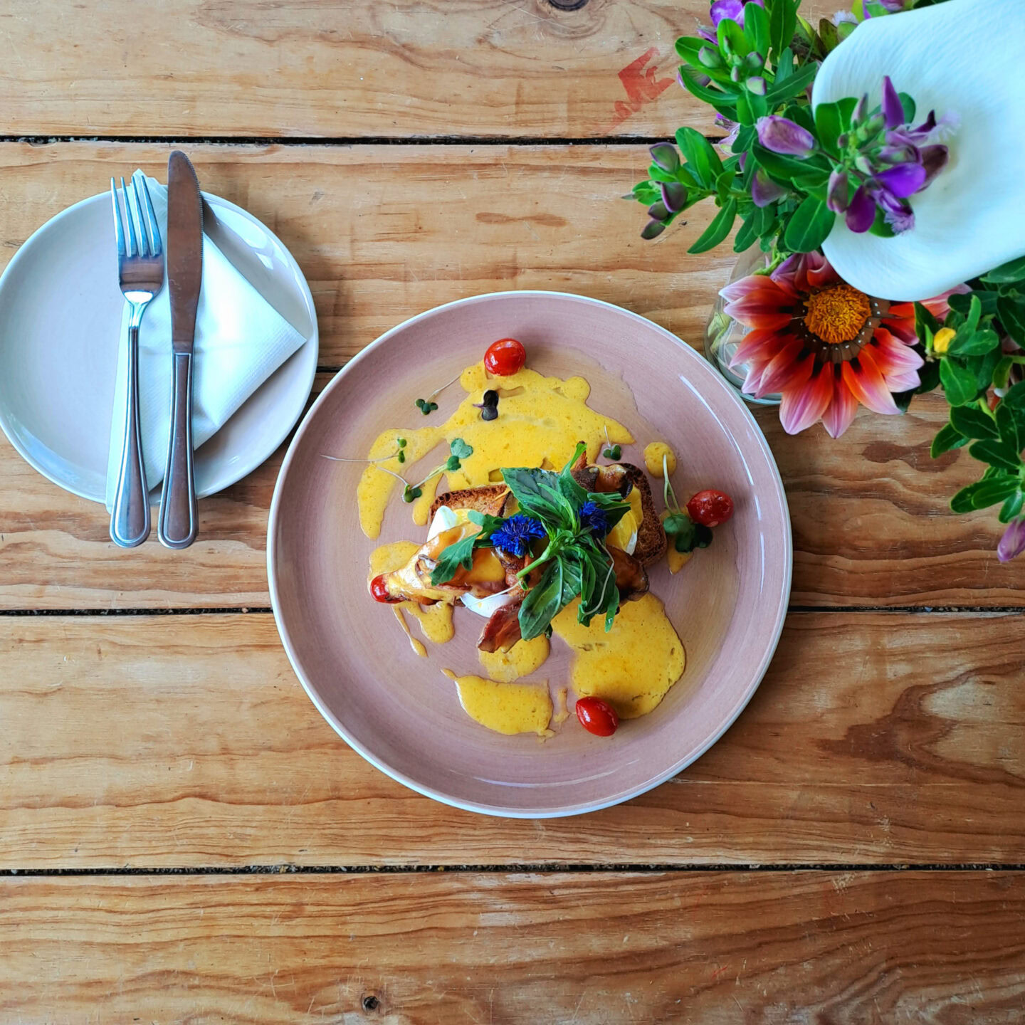 A plated dish with a yellow sauce, herbs and cherry tomatoes on a timber table, Old Mac Daddy, Elgin Valley