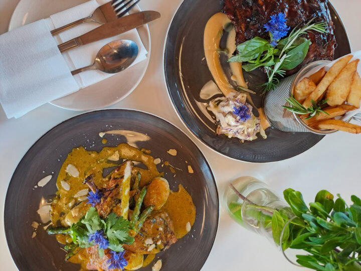 Two plated main courses on a white table, one with fries and coleslaw, Old Mac Daddy, Elgin Valley
