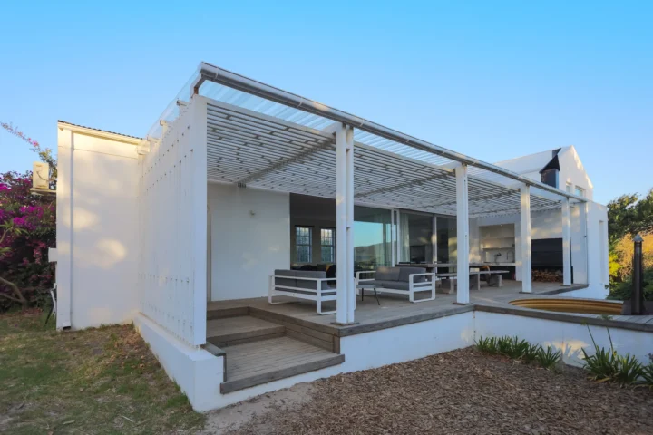 Home The School House: white gabled house with a slatted pergola over the patio and outdoor seating, Old Mac Daddy, Elgin Valley