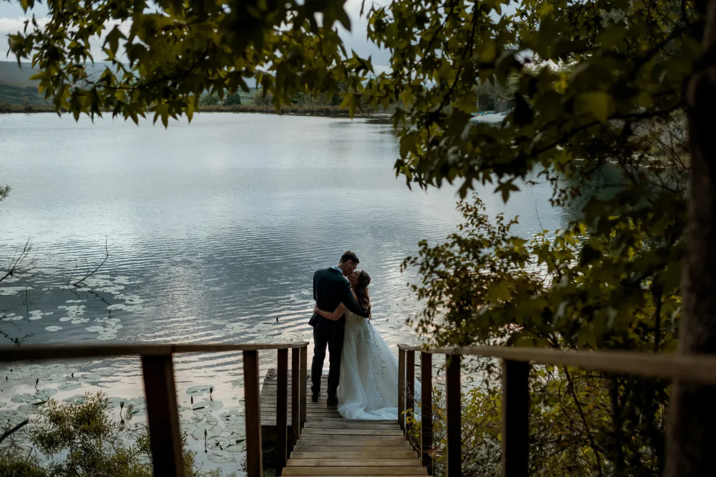 Weddings & Events Couple embracing on the jetty, lake and hills behind, Old Mac Daddy, Elgin Valley