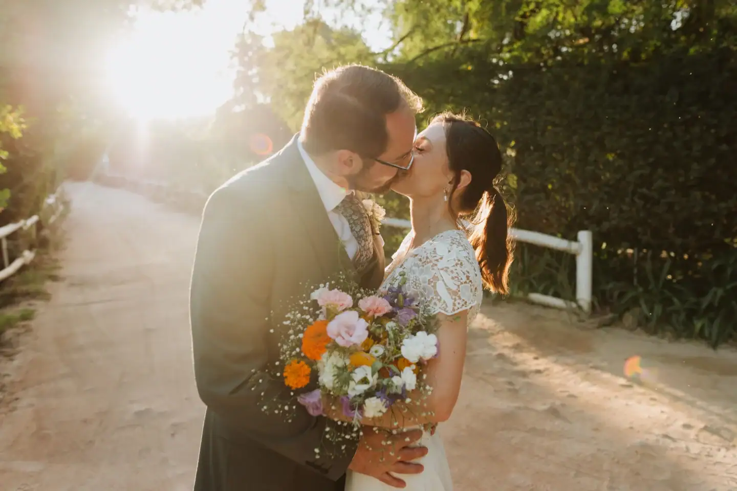Bride and groom kissing on a sunlit lane, a wildflower bouquet in her hand, Old Mac Daddy, Elgin Valley