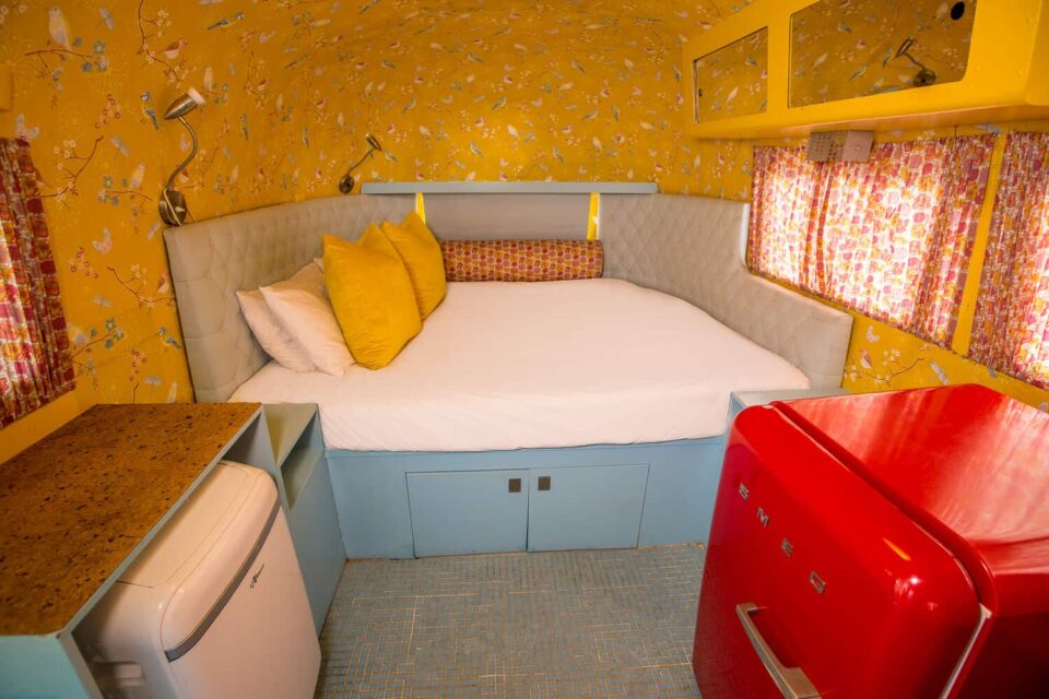 Birdy: bed with yellow cushions, bird-print wallpaper and a red SMEG fridge, Old Mac Daddy, Elgin Valley