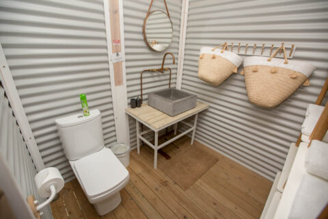 Daddy's Hideaway: bathroom with a basin, round mirror and woven baskets on corrugated-iron walls, Old Mac Daddy, Elgin Valley