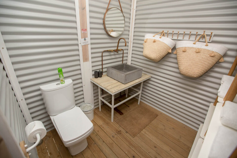 Daddy's Hideaway: bathroom with a basin, round mirror and woven baskets on corrugated-iron walls, Old Mac Daddy, Elgin Valley