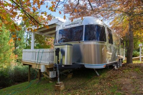 Love Cake: silver Airstream beside its timber deck under autumn trees, Old Mac Daddy, Elgin Valley