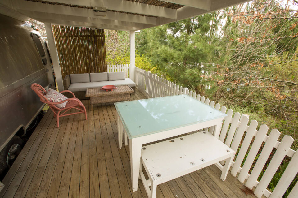 Love Cake: covered deck with a dining table and lounge seating beside the Airstream, Old Mac Daddy, Elgin Valley