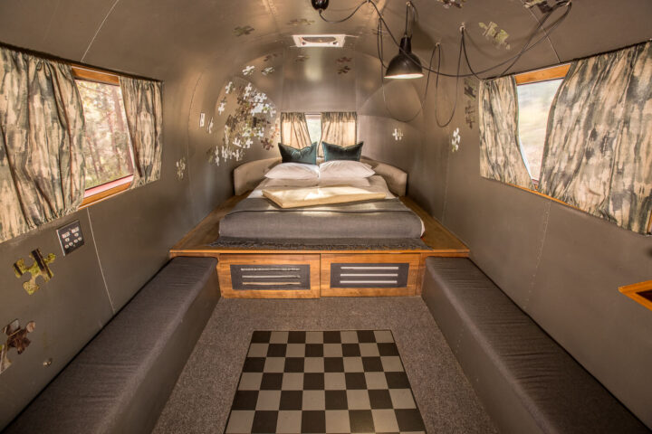 Metalmorphosis: raised Airstream bed, grey banquettes and a chequered floor panel, puzzle-piece decor, Old Mac Daddy, Elgin Valley