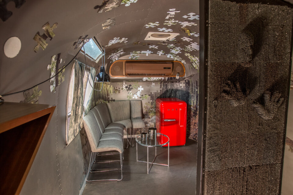 Metalmorphosis: grey lounge seating and a red SMEG fridge, puzzle pieces on the walls, Old Mac Daddy, Elgin Valley
