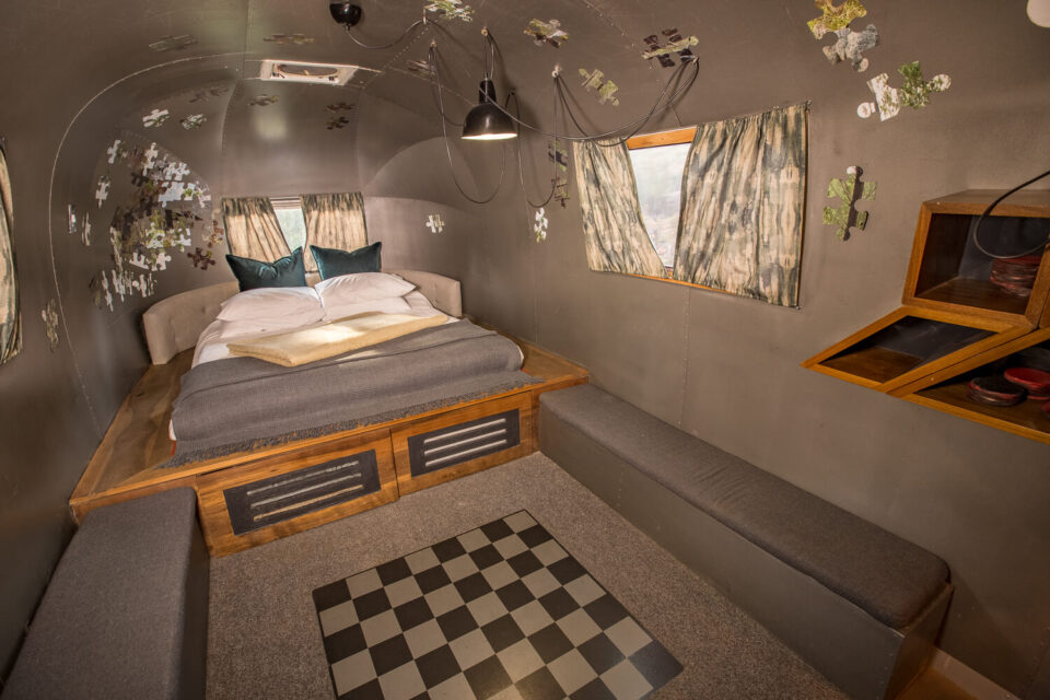 Metalmorphosis: raised Airstream bed, grey banquettes and a chequered floor panel, puzzle-piece decor, Old Mac Daddy, Elgin Valley