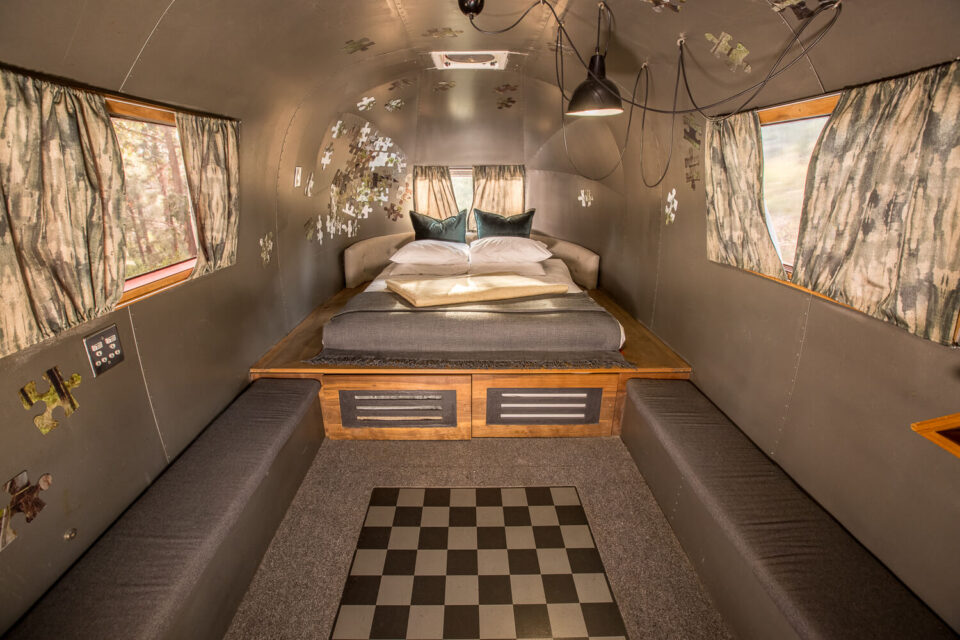 Metalmorphosis: raised Airstream bed, grey banquettes and a chequered floor panel, puzzle-piece decor, Old Mac Daddy, Elgin Valley