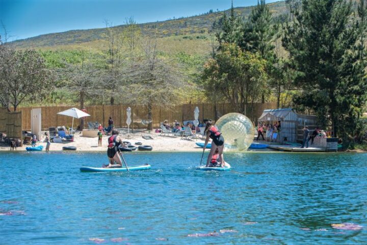 Paddle boarders and a water zorb on the lake in front of the busy beach, Old Mac Daddy, Elgin Valley