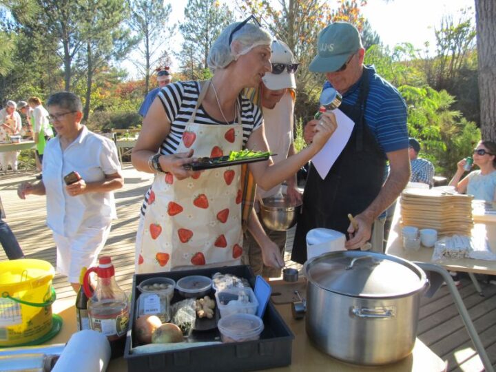 Team members in aprons and hairnets at an outdoor cooking challenge, Old Mac Daddy, Elgin Valley