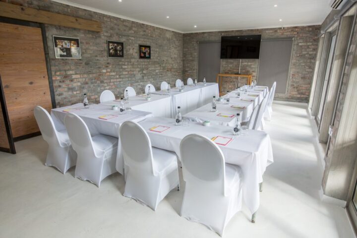 Conference room with two long tables, white chair covers and a wall screen, Old Mac Daddy, Elgin Valley