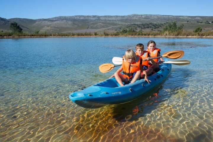 Three children in life jackets paddling a kayak on the lake, Old Mac Daddy, Elgin Valley