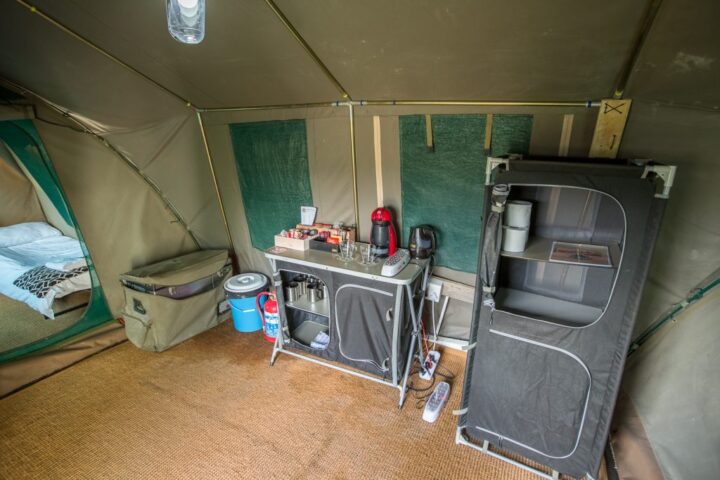 Inside a canvas tent: a camp kitchen unit with a kettle, a coffee machine and a folding cupboard, Old Mac Daddy, Elgin Valley