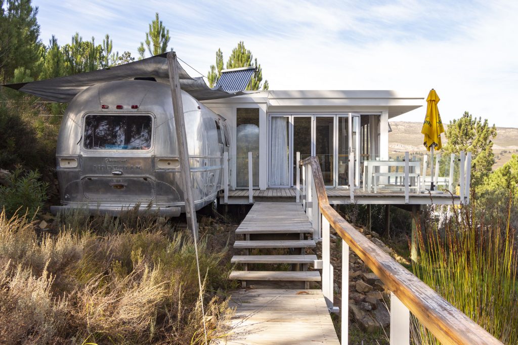 An Airstream and its glass-fronted deck, reached by timber steps through the fynbos, Old Mac Daddy, Elgin Valley