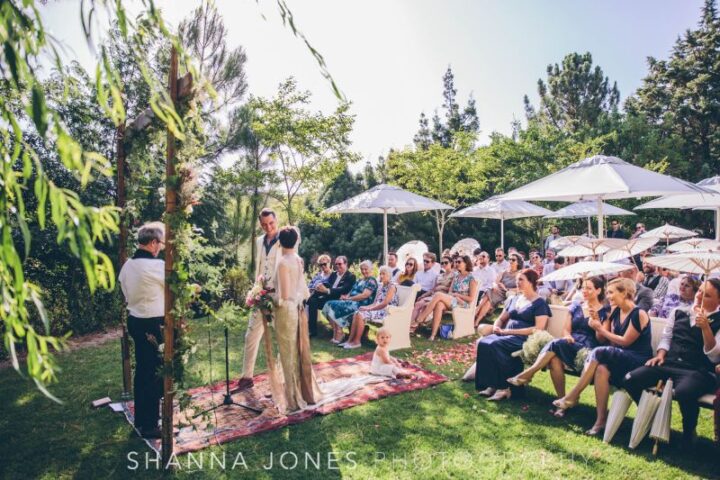 A couple exchanging vows on the lawn with guests seated under white umbrellas, Old Mac Daddy, Elgin Valley