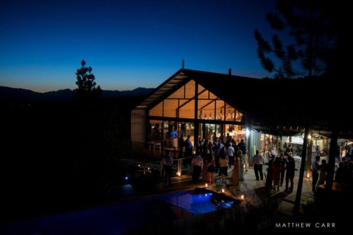Wedding guests outside the lit-up Barn at dusk, Old Mac Daddy, Elgin Valley