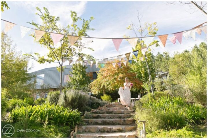 A bride walking down stone garden steps beneath bunting, Old Mac Daddy, Elgin Valley